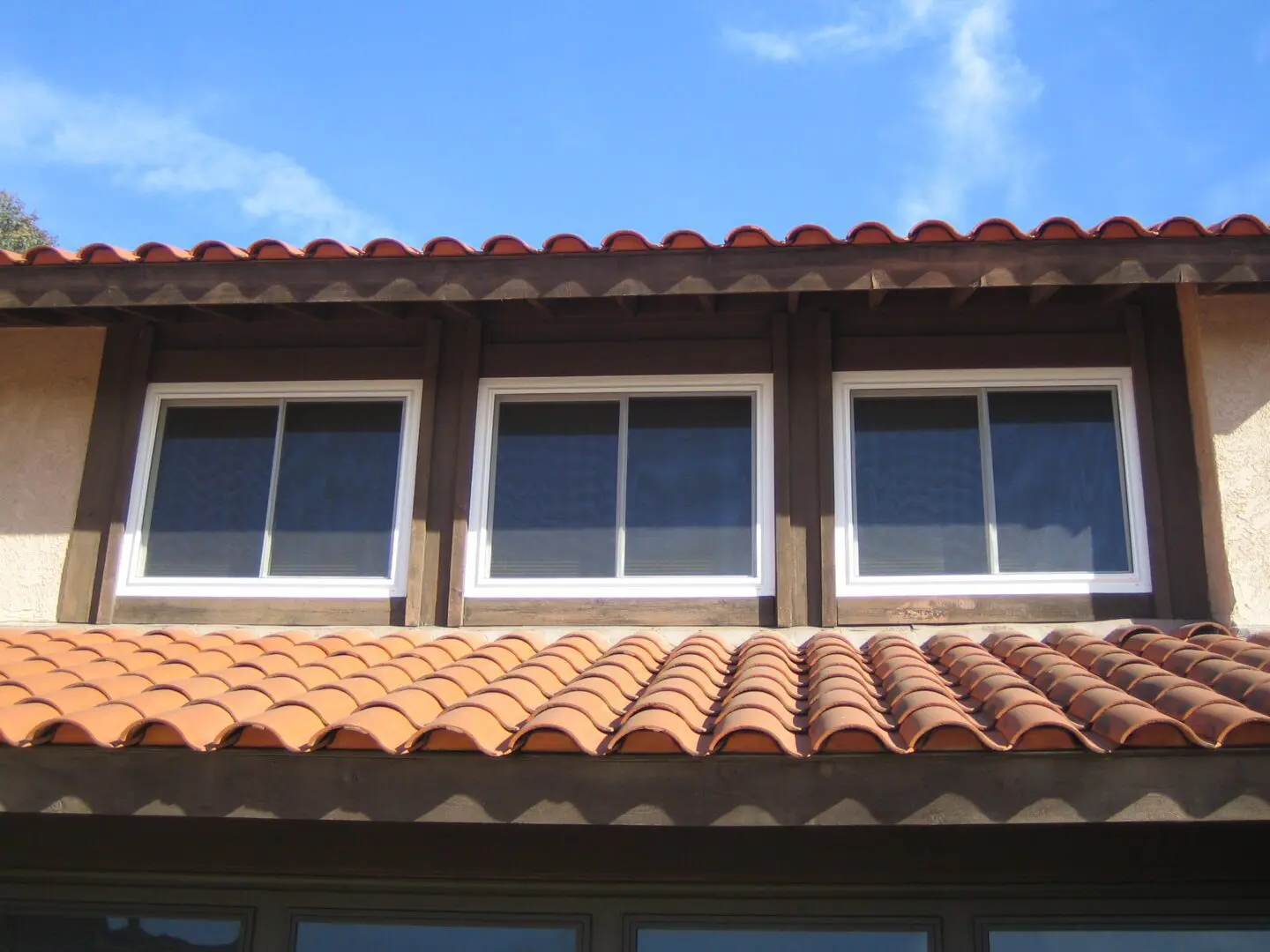 A brown roof with three windows and a red tile roof.
