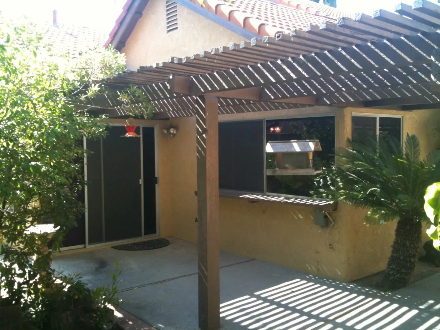 A patio with a pergola and two doors.