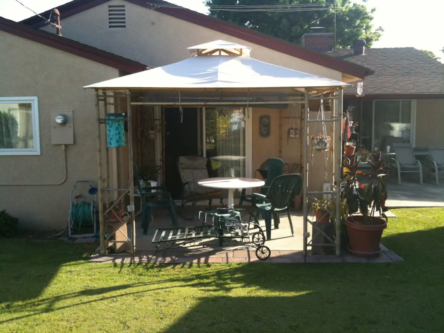 A patio with tables and chairs in the middle of a yard.