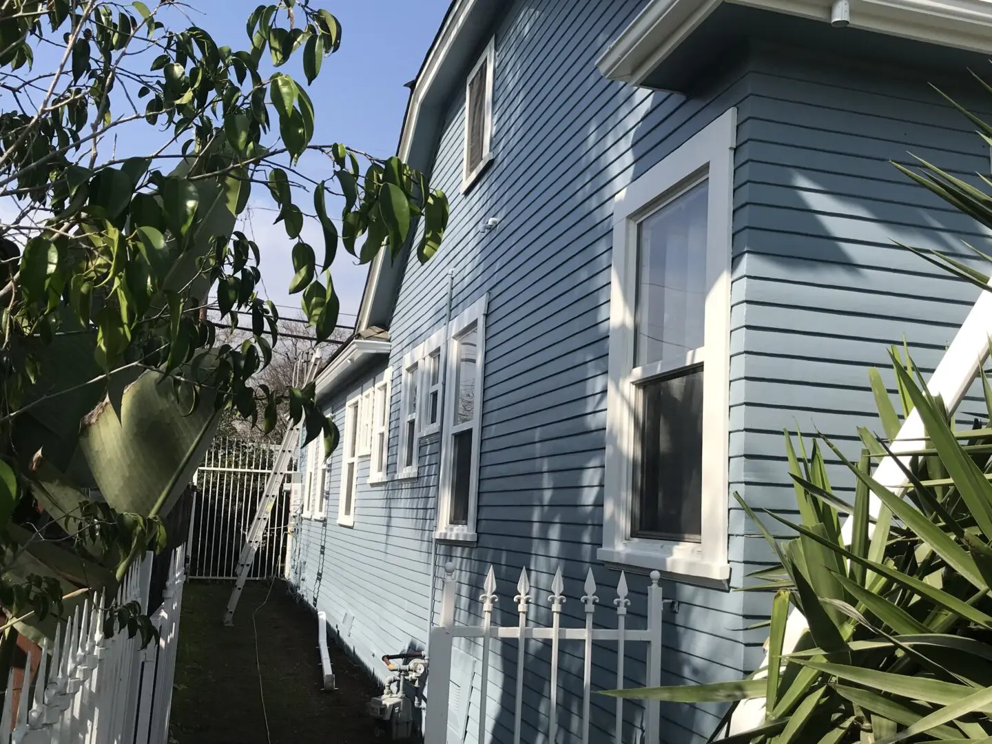 A blue house with white trim and a fence.