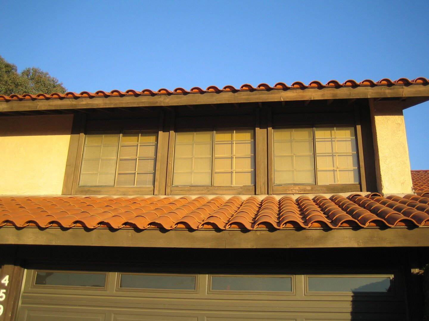 A brown house with a red roof and two windows.