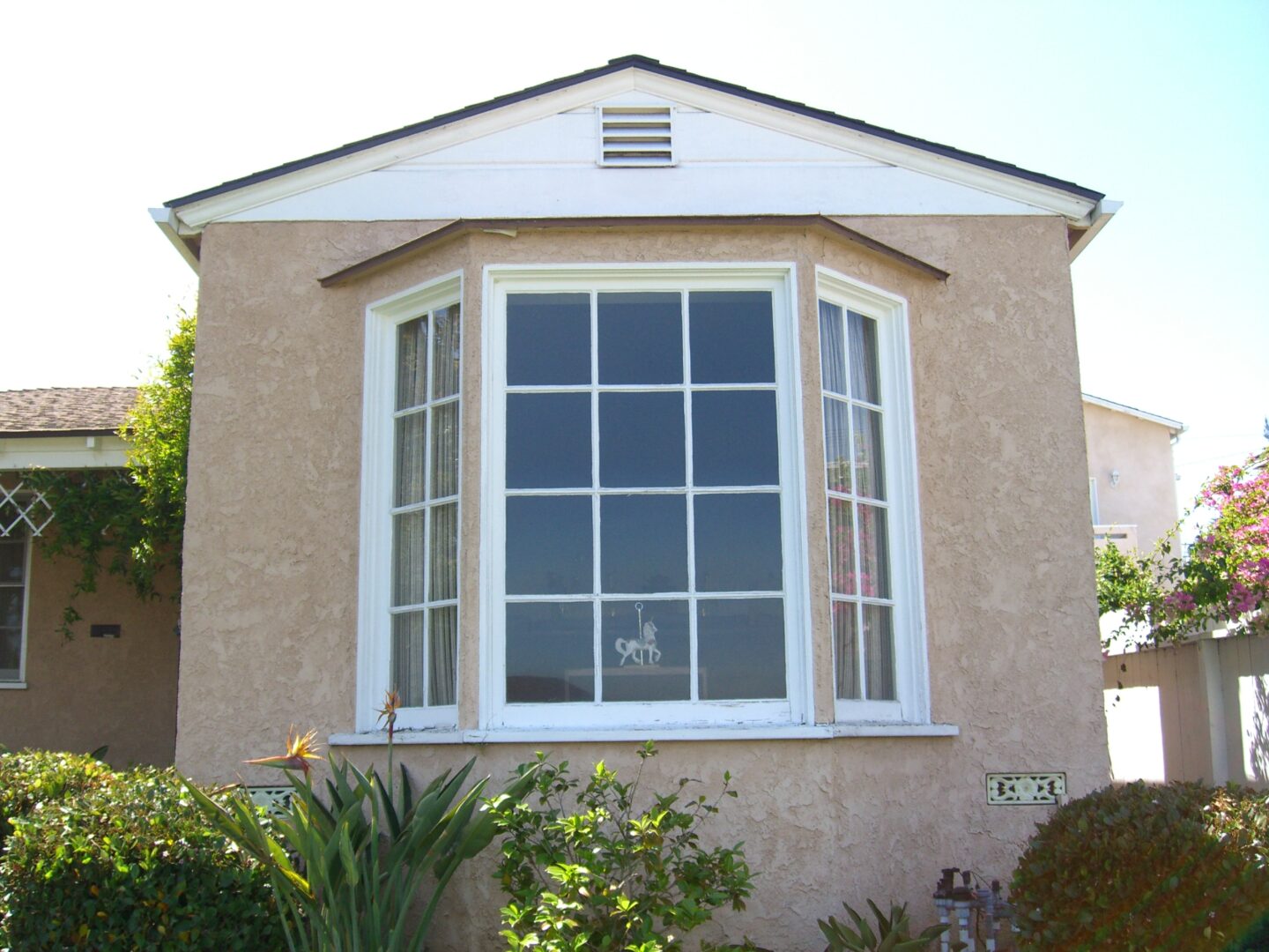 A house with a large window and plants outside.