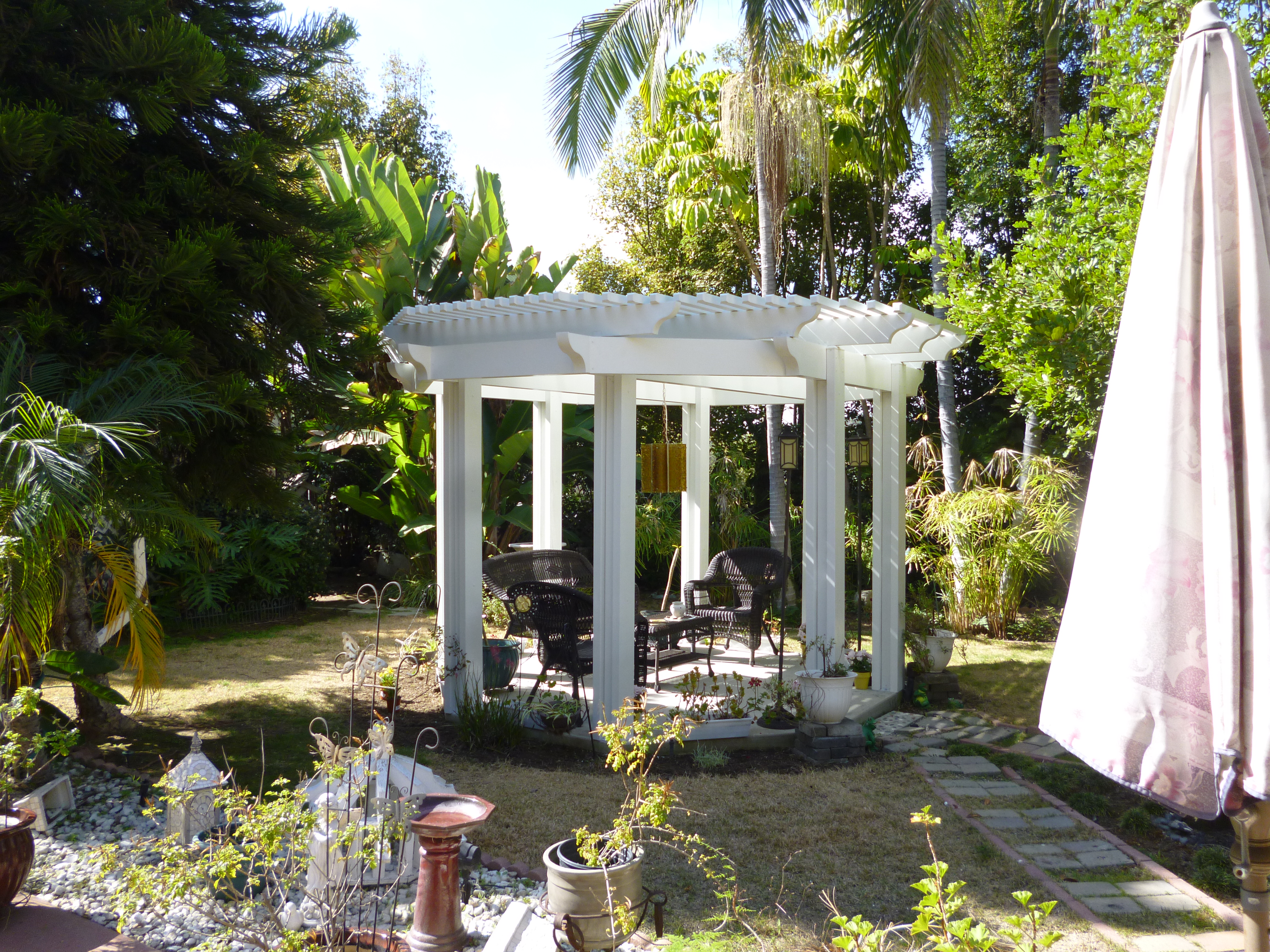 A gazebo with a white structure in the middle of a garden.