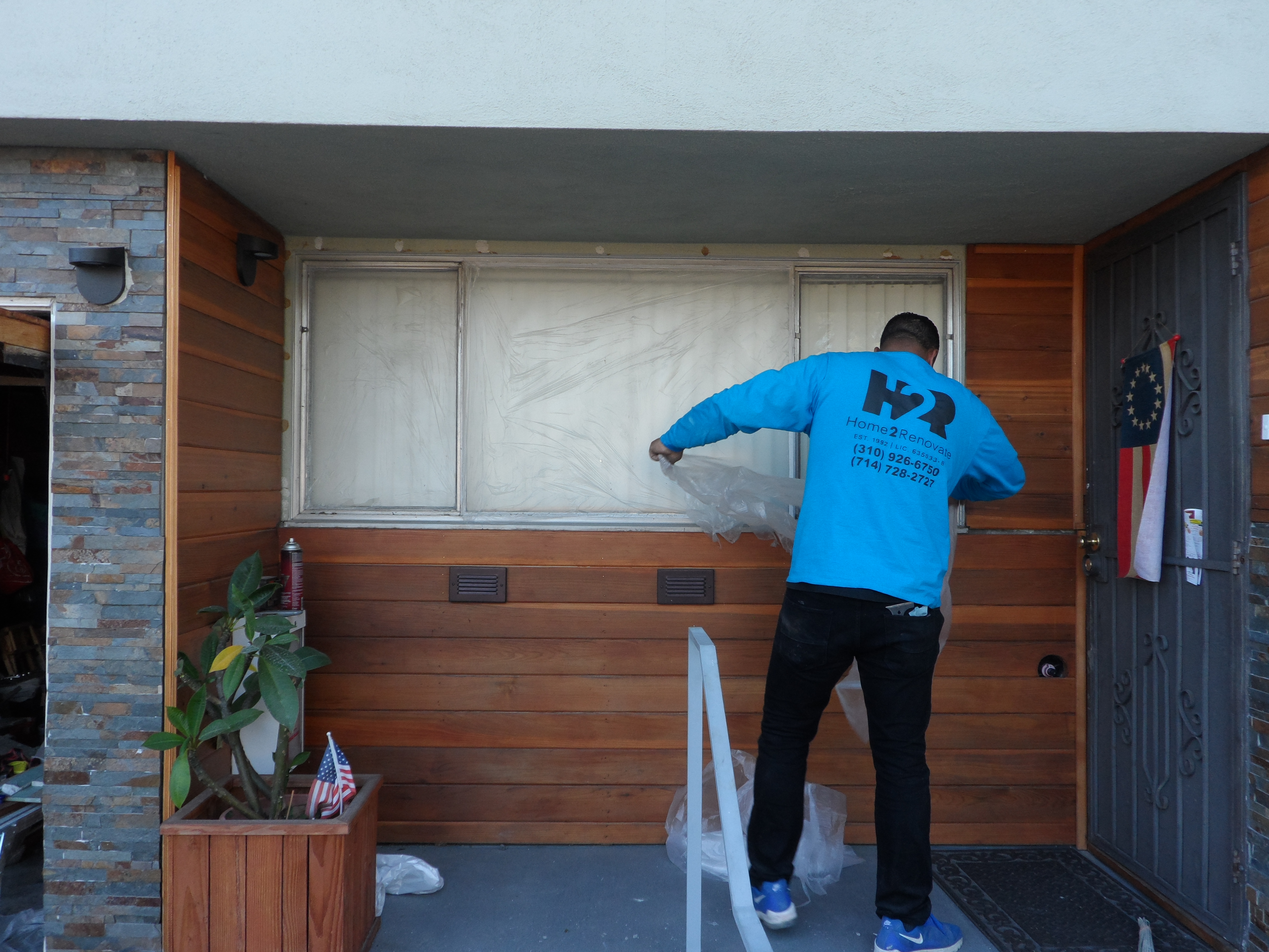 A man in blue shirt painting a wall.