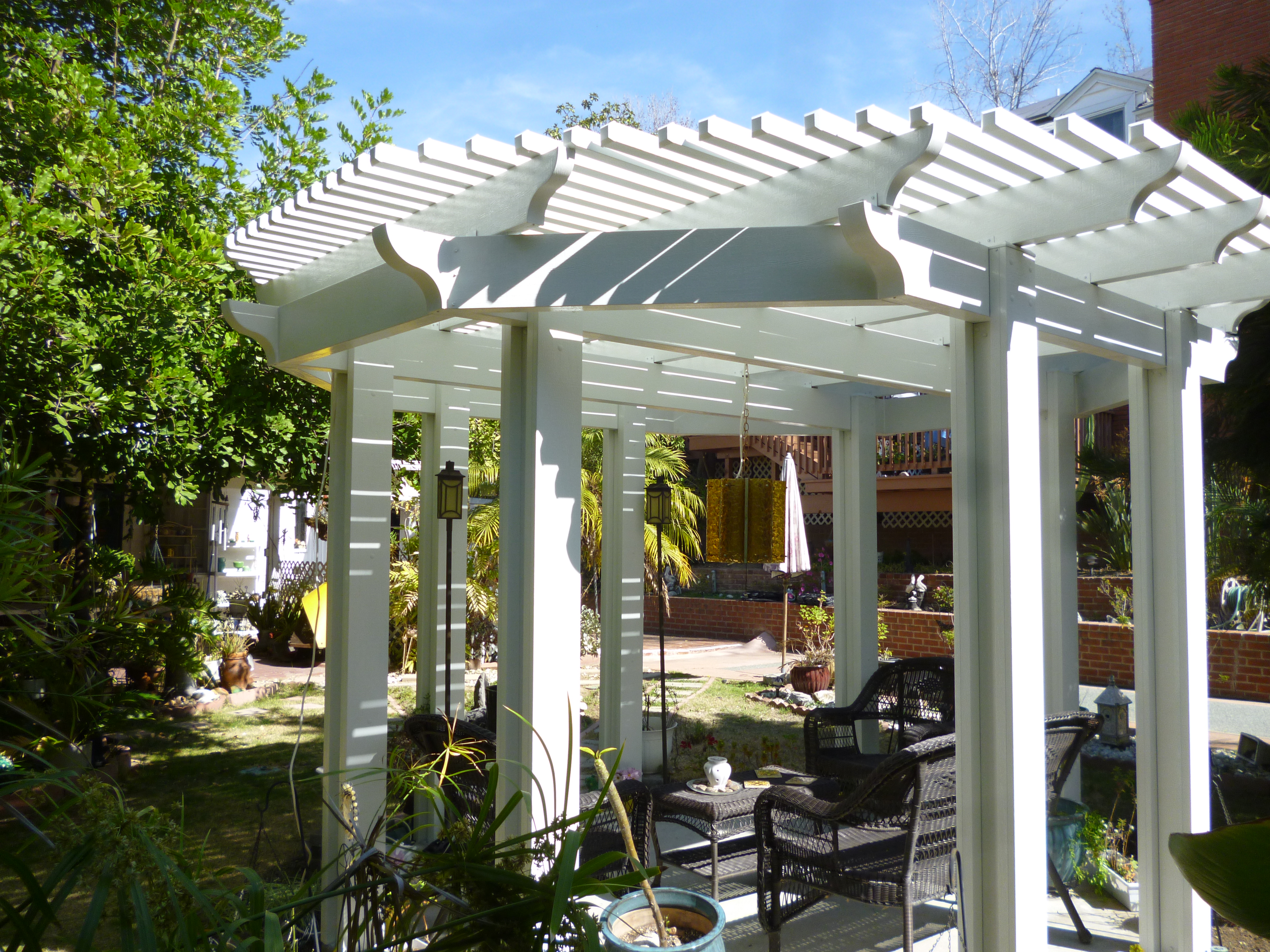 A white pergola with chairs and tables in the background.