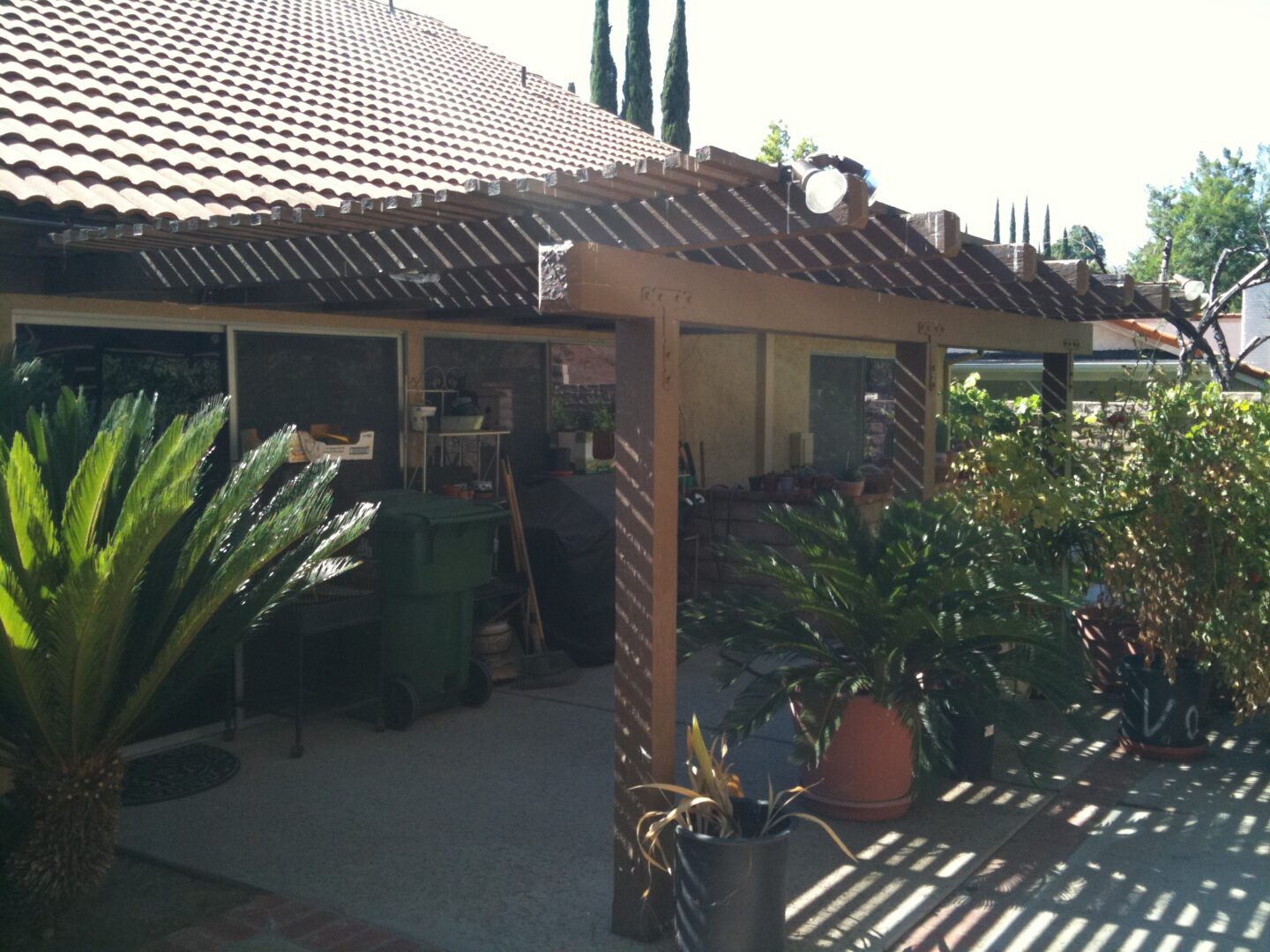 A man standing in front of a patio with potted plants.