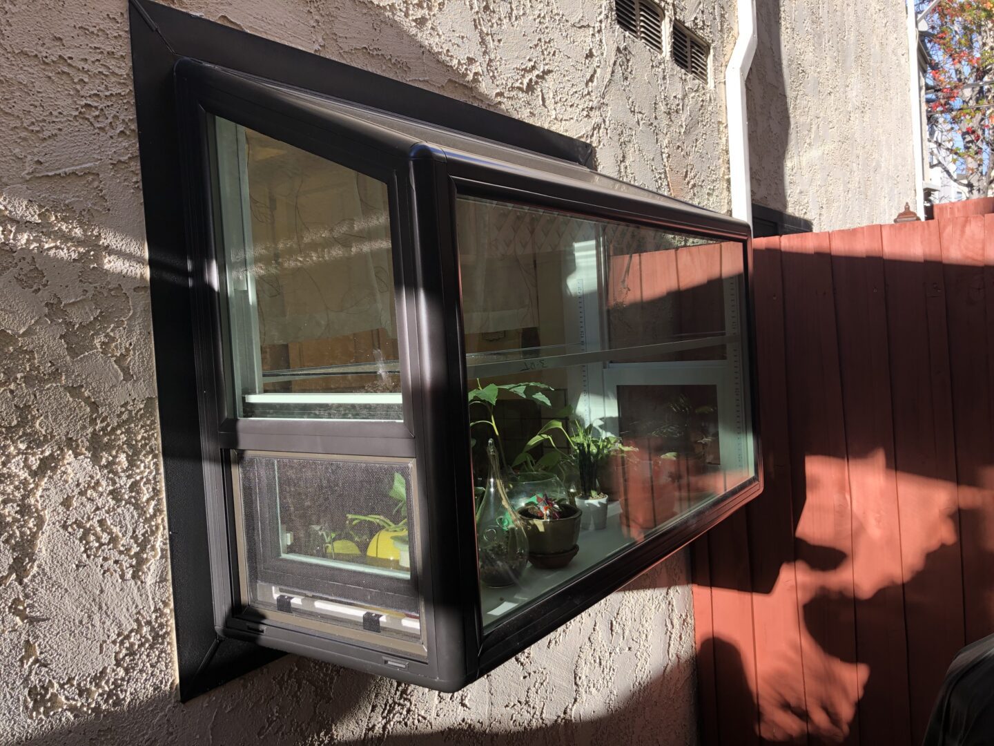 A window with a plant in it on the side of a building.