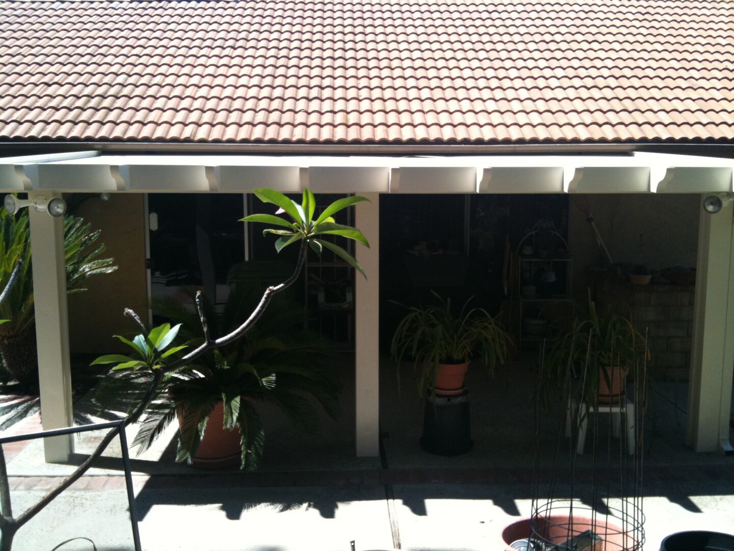 A patio with potted plants and a red tile roof.