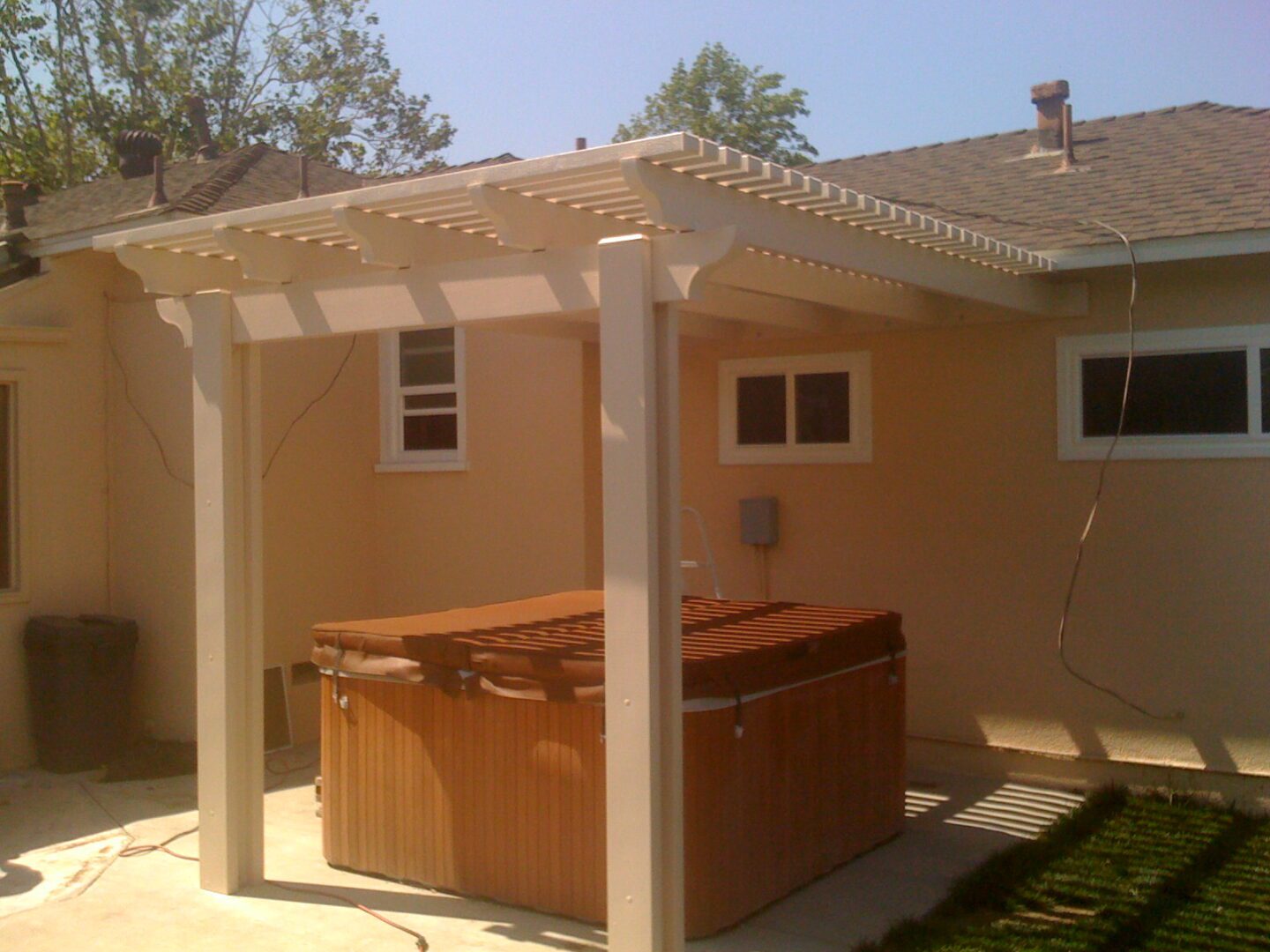 A hot tub is under the pergola in this backyard.