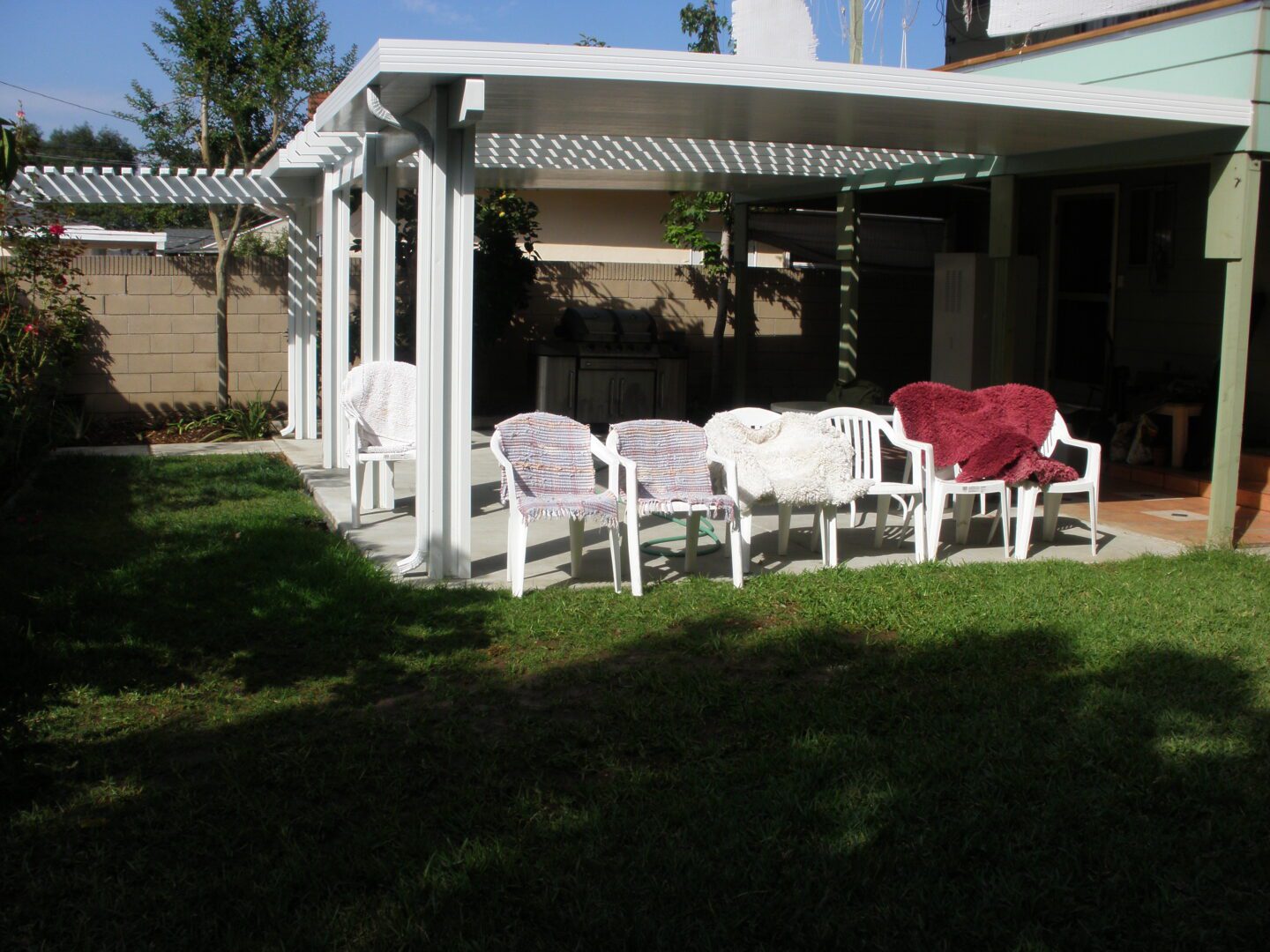 A patio with white chairs and red heart pillow.