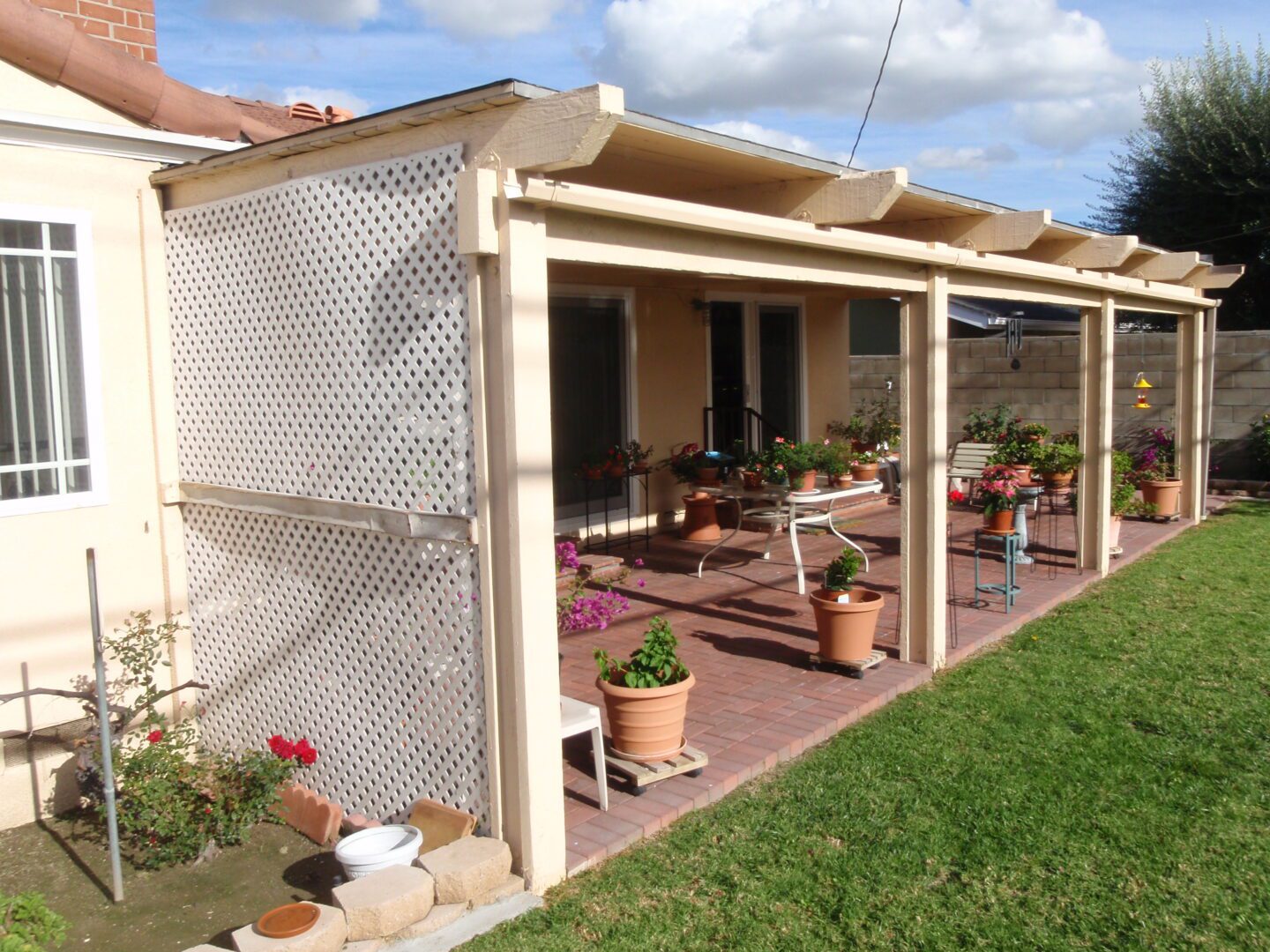 A patio with potted plants and a pergola.