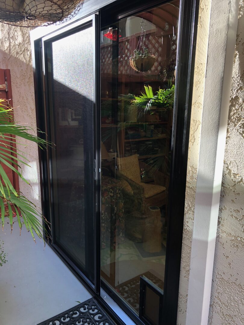 A black sliding glass door with a reflection of the outside.