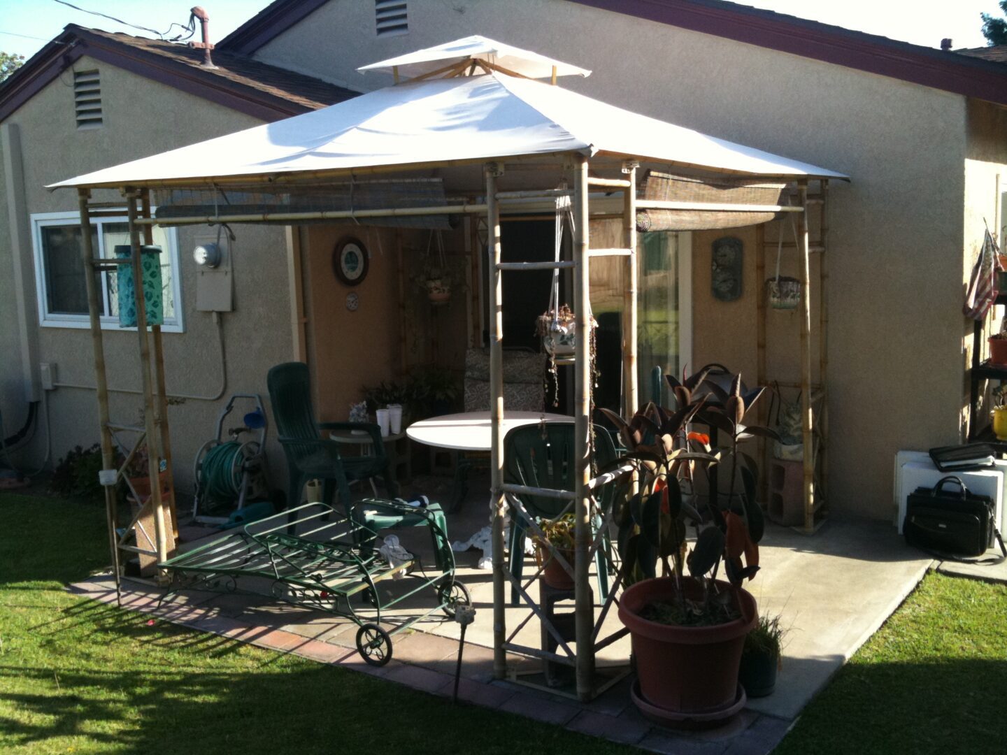 A gazebo with chairs and tables in the back yard.