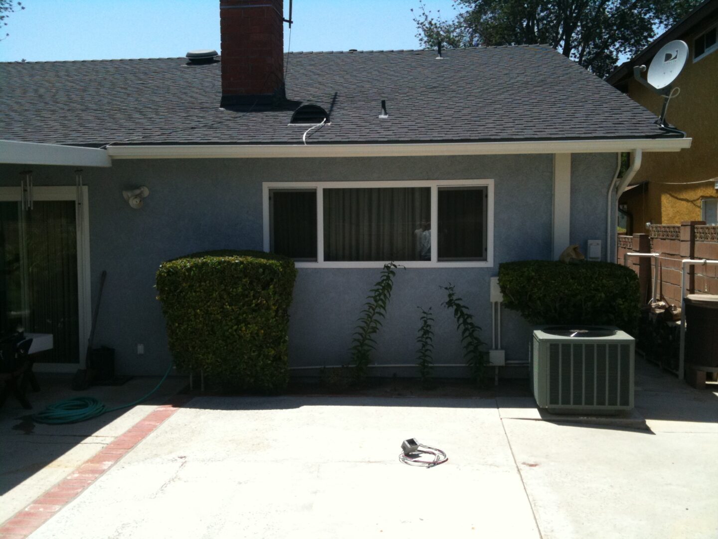 A house with a cat sitting on the ground outside.