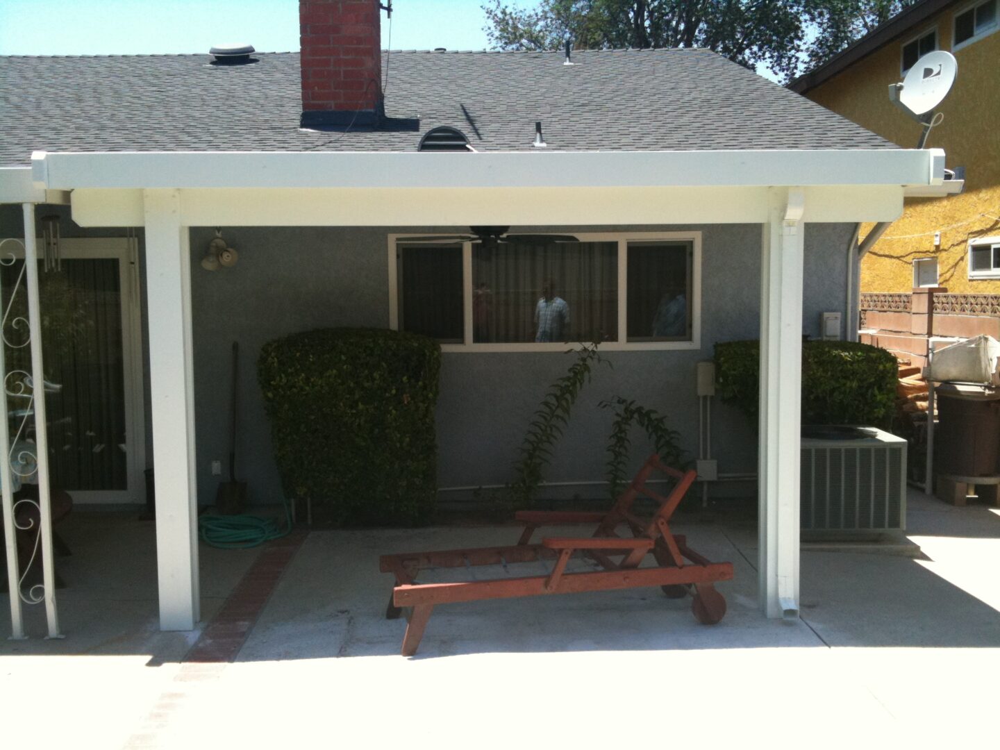 A patio with a bench and a covered area.