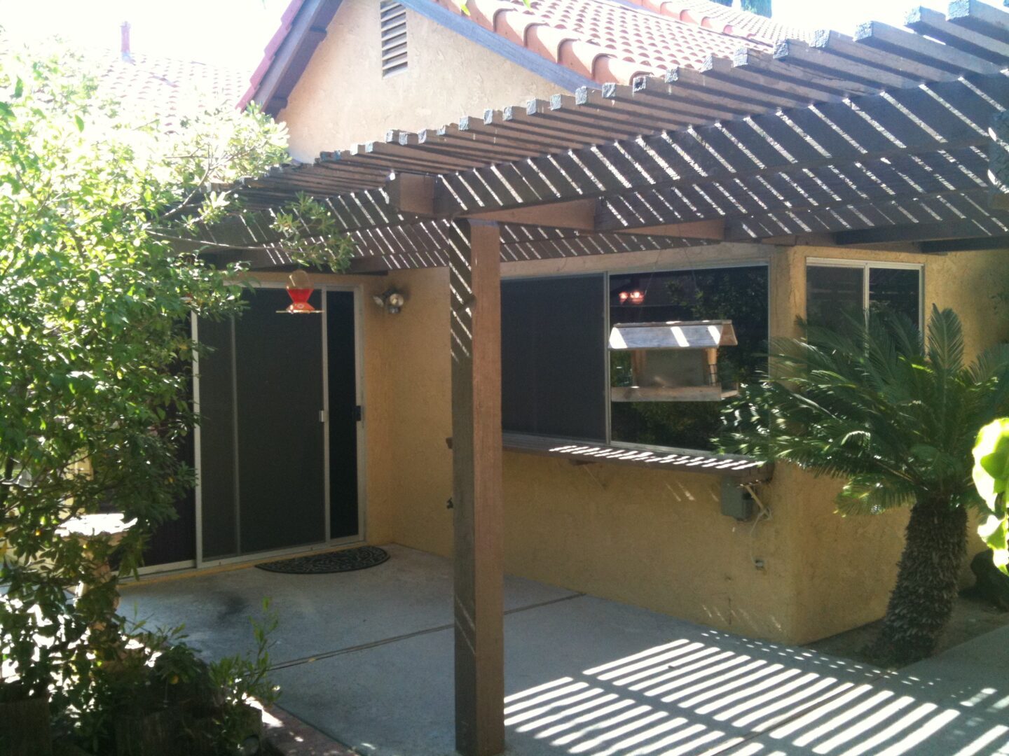 A patio with a pergola and two doors.