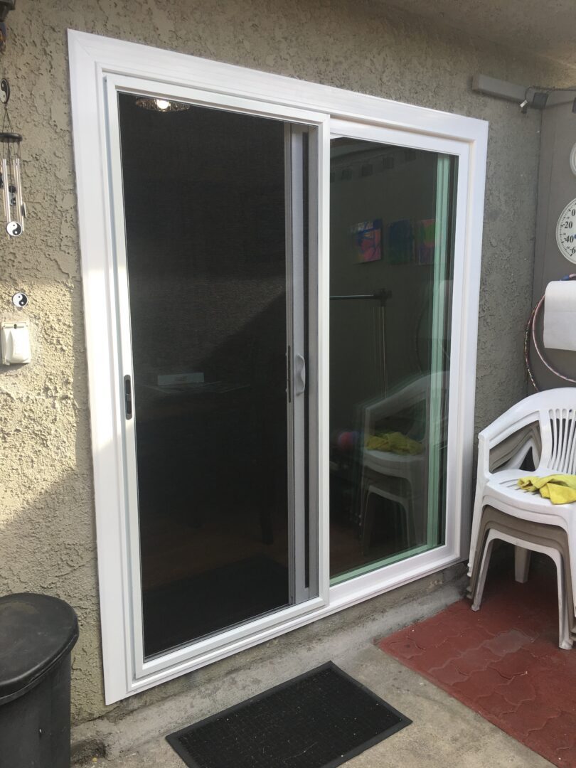 A white sliding glass door in the middle of an outdoor patio.