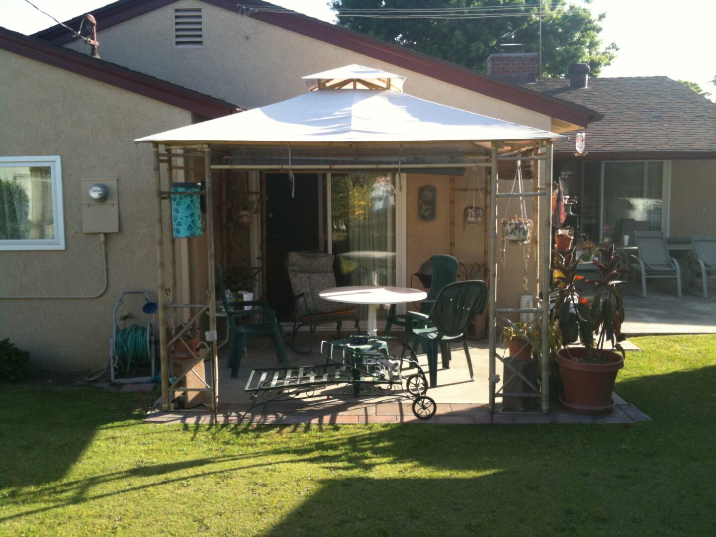 A patio with tables and chairs in the middle of a yard.