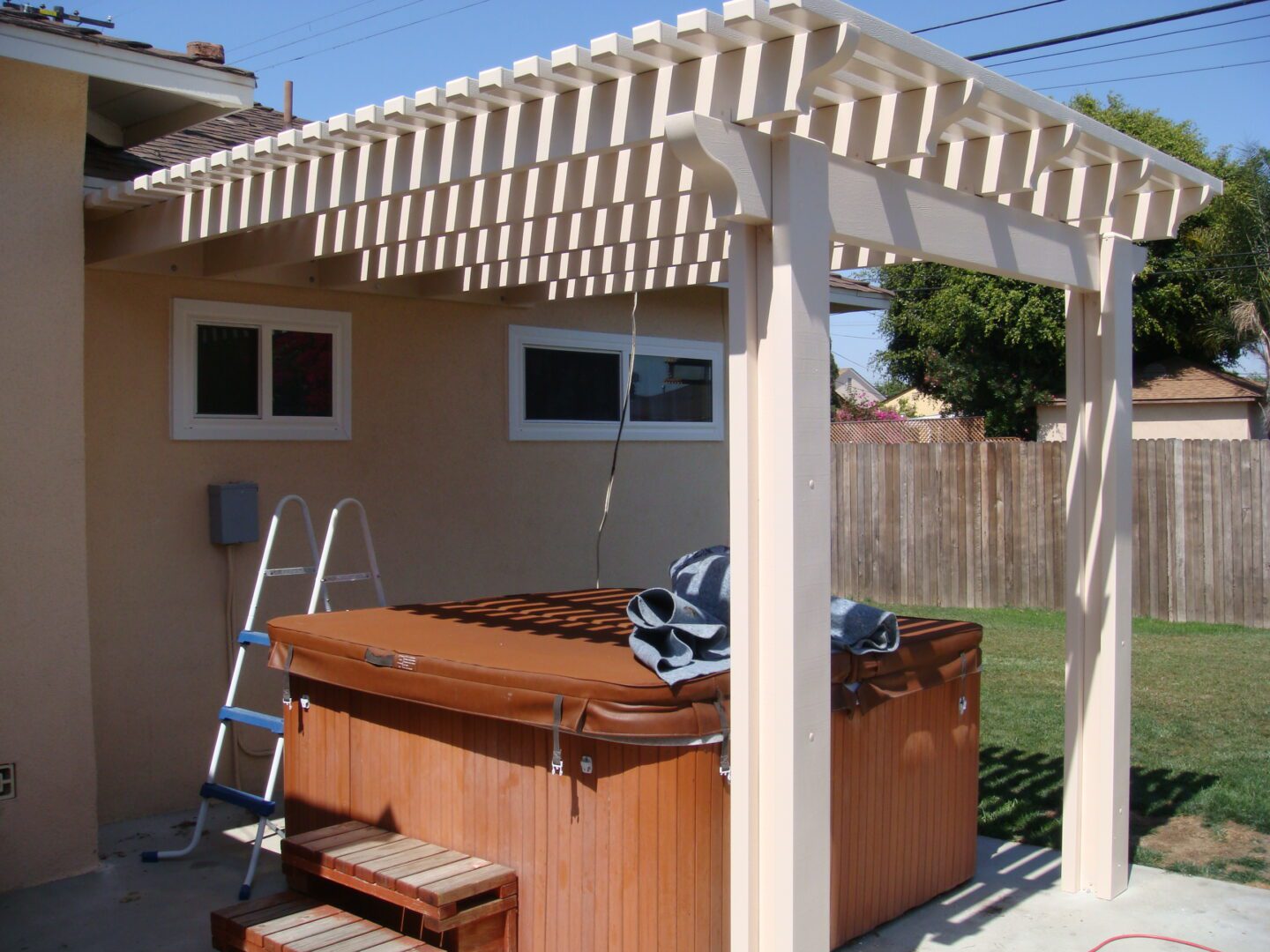 A hot tub under an arbor in the backyard.