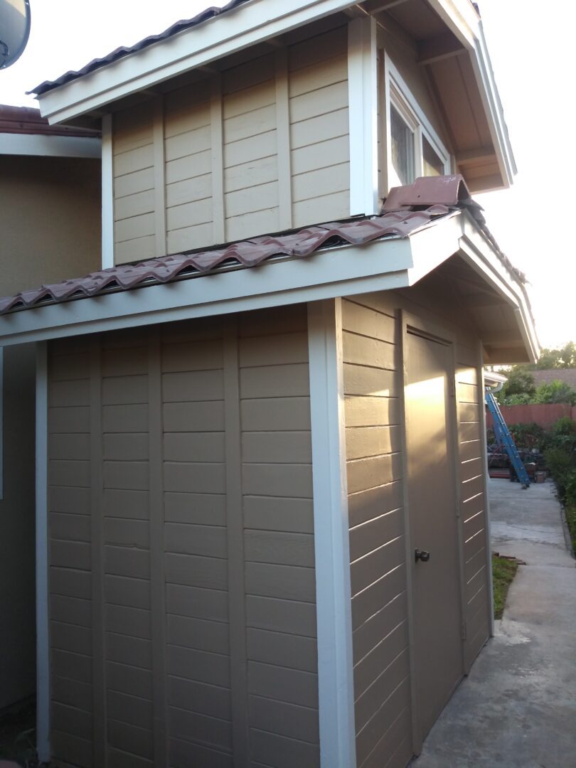 A brown shed with a metal roof and two windows.