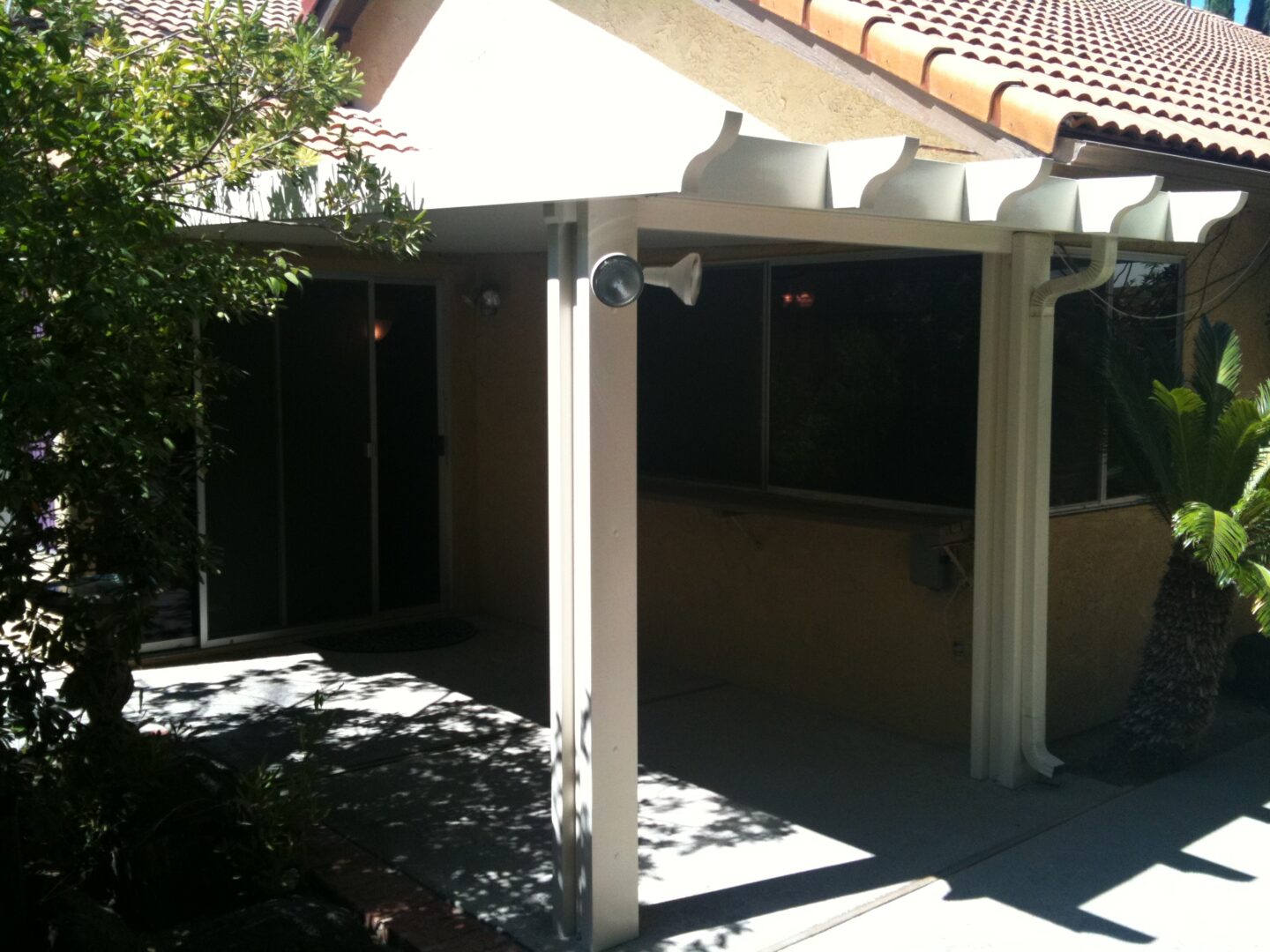 A patio cover with an open door and a view of the back yard.