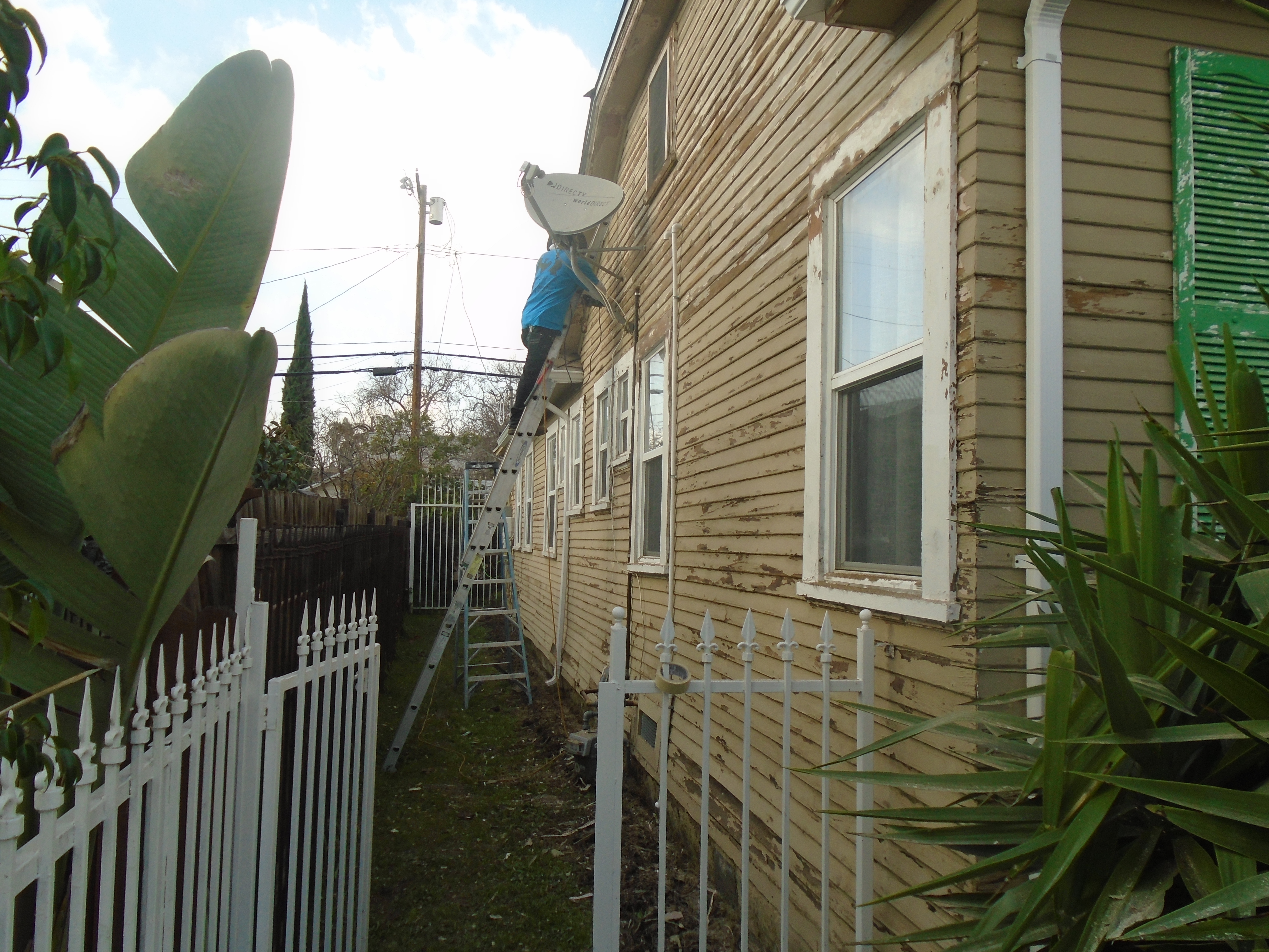 A house with a white fence and a blue satellite dish.