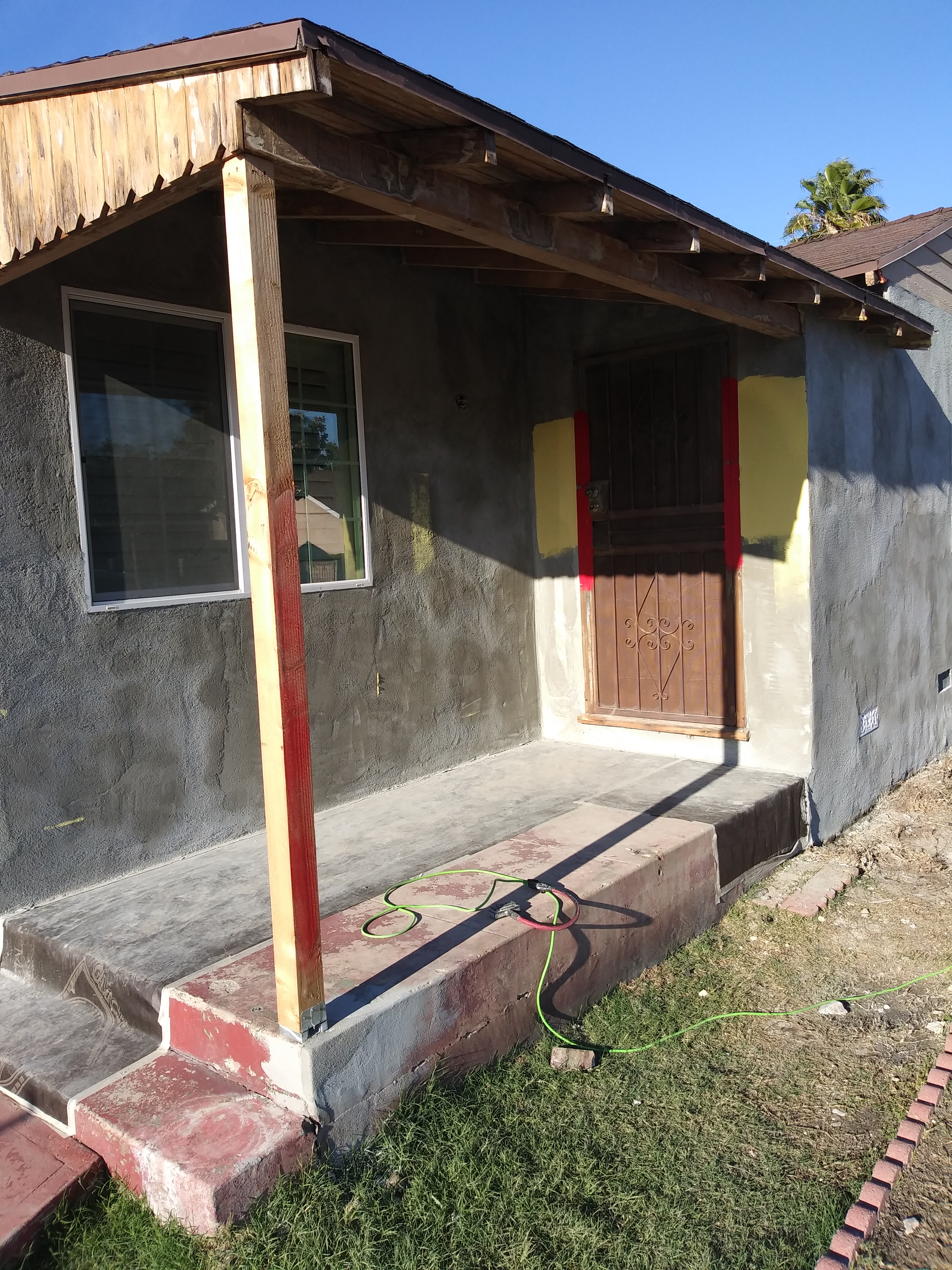 A porch with a door and windows on the side of it.