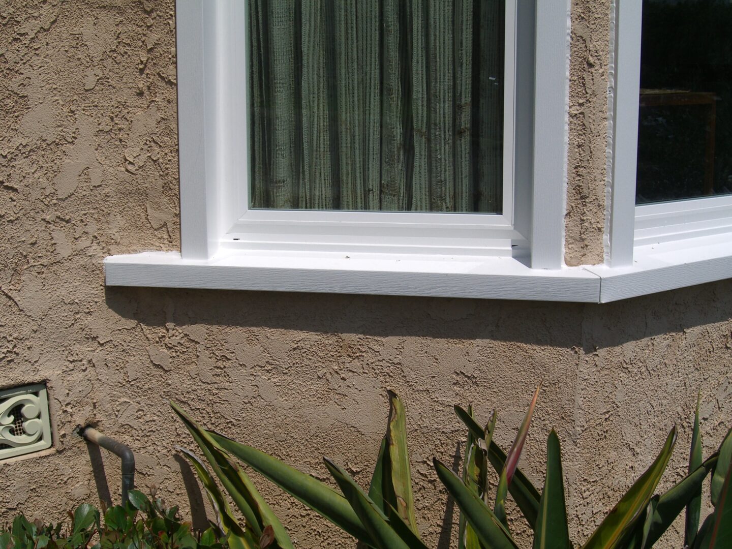 A window with green curtains on the outside of a house.