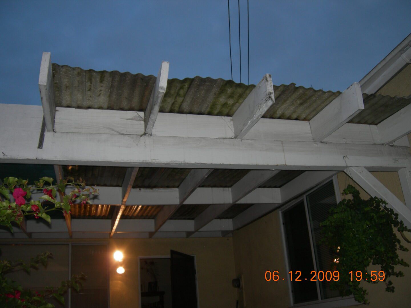 A white pergola with a green roof and lights