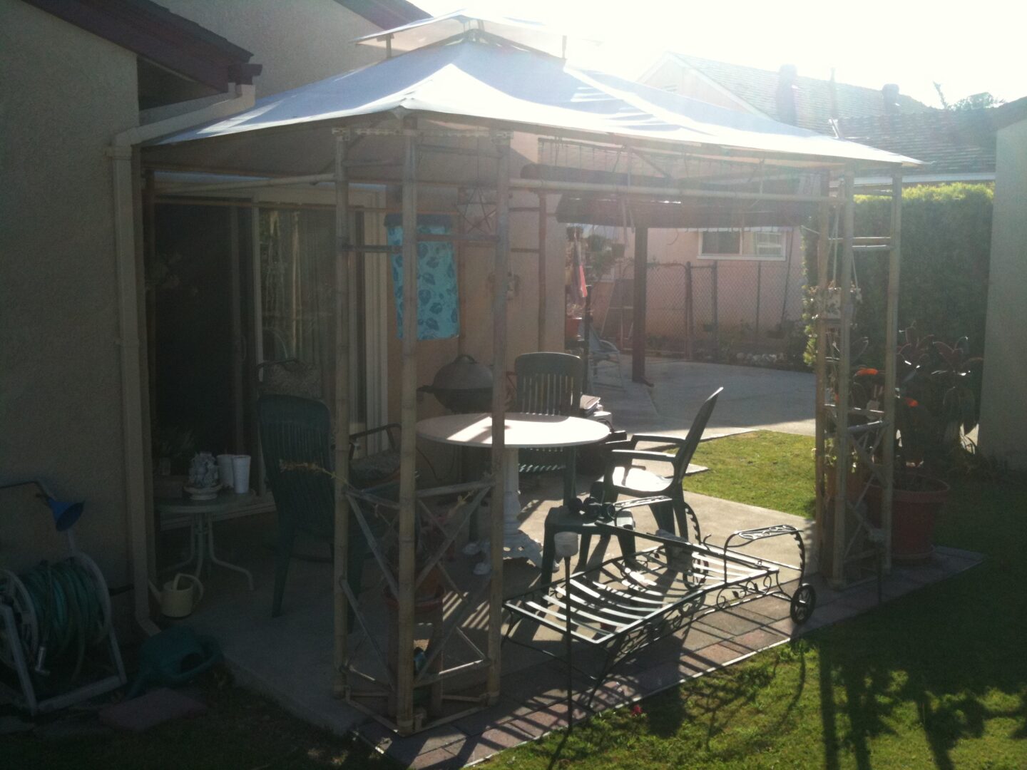 A gazebo with chairs and tables in the middle of a yard.