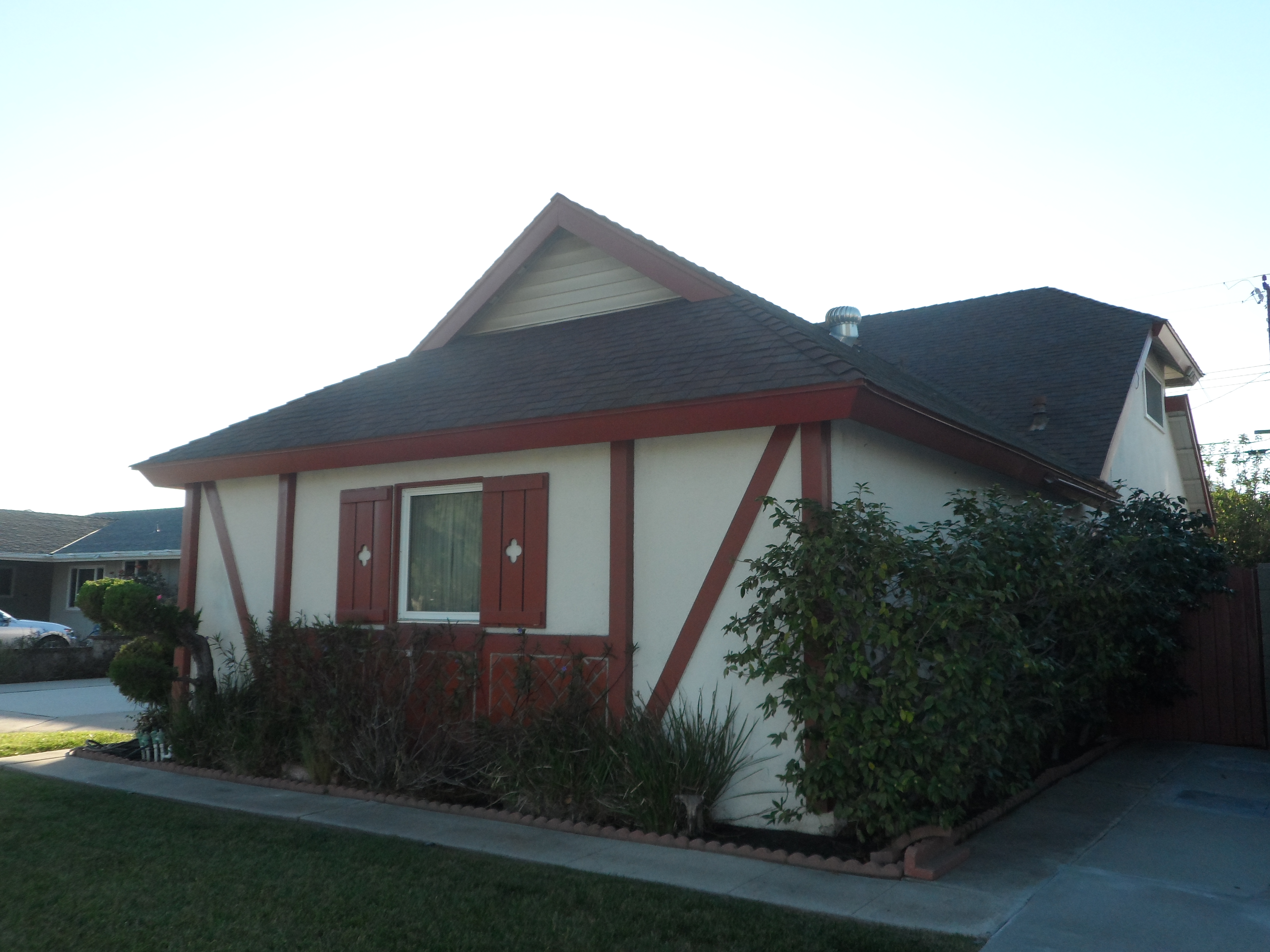 A white house with red trim and shutters.