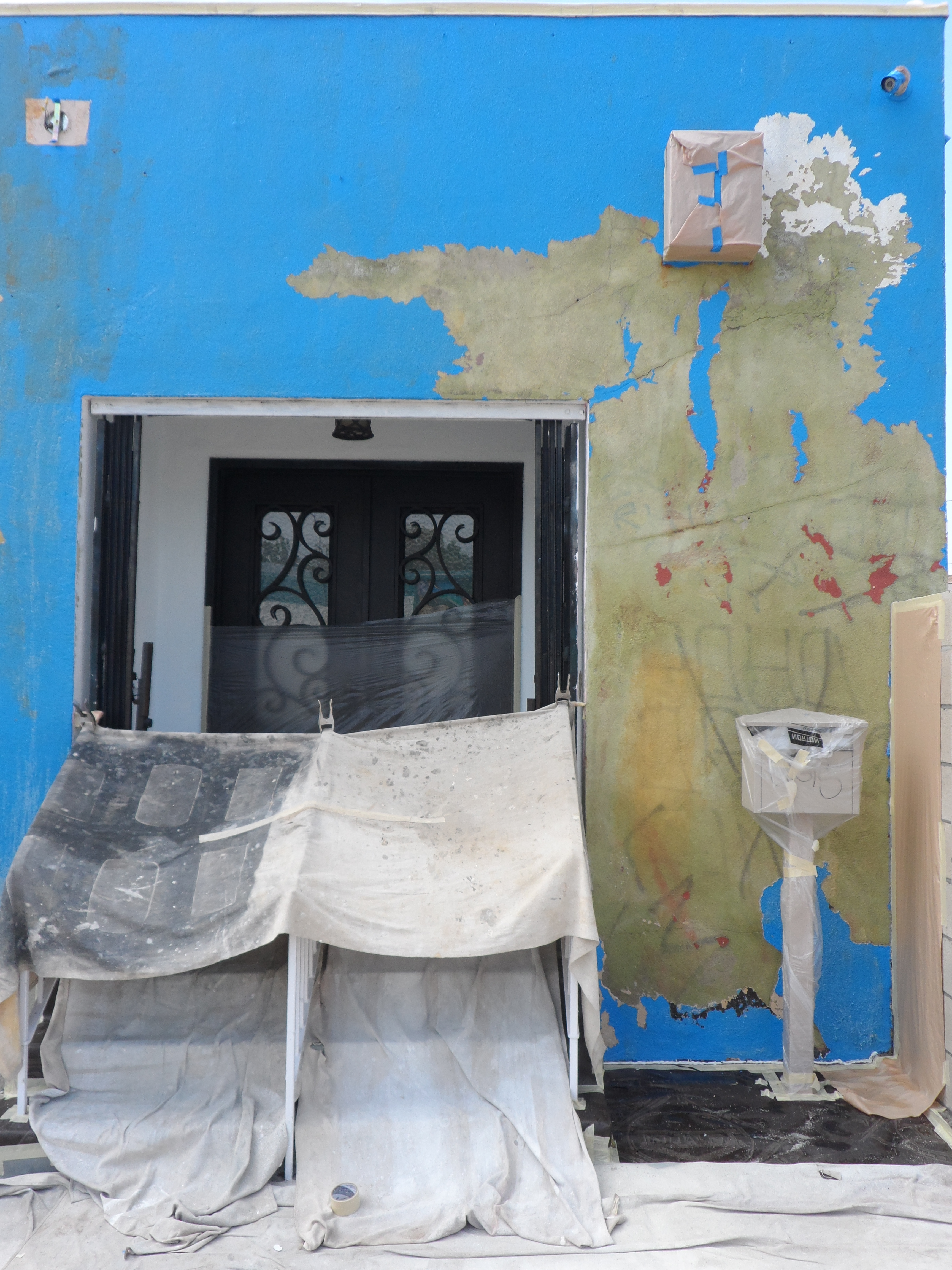 A blue wall with peeling paint and a door.