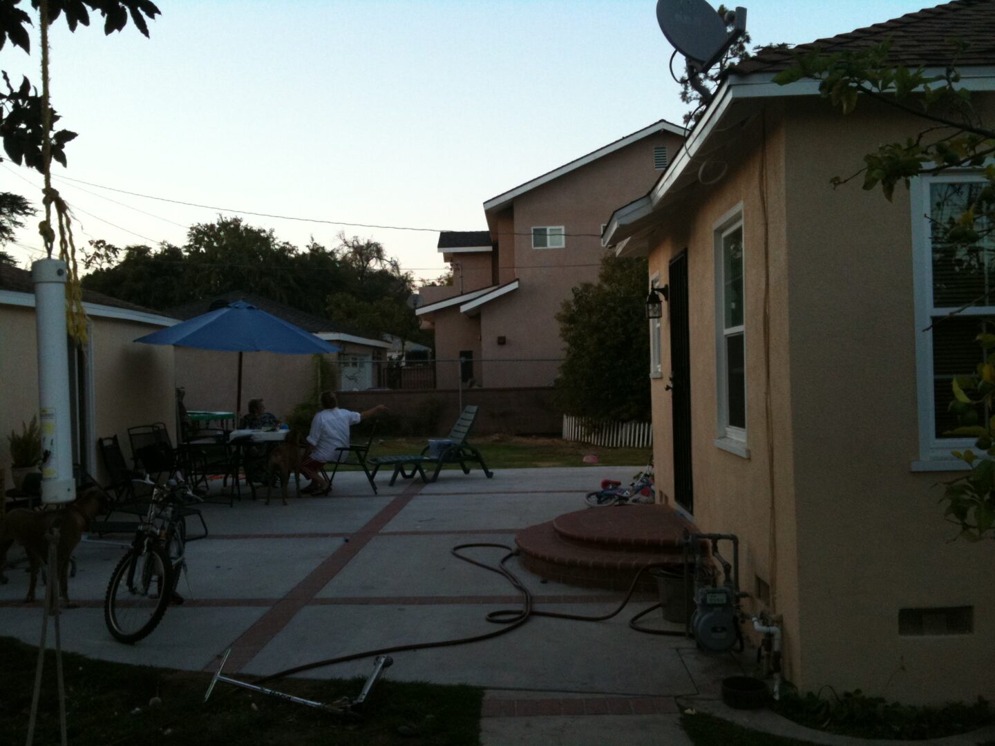 A backyard with people sitting on the patio and a bicycle.