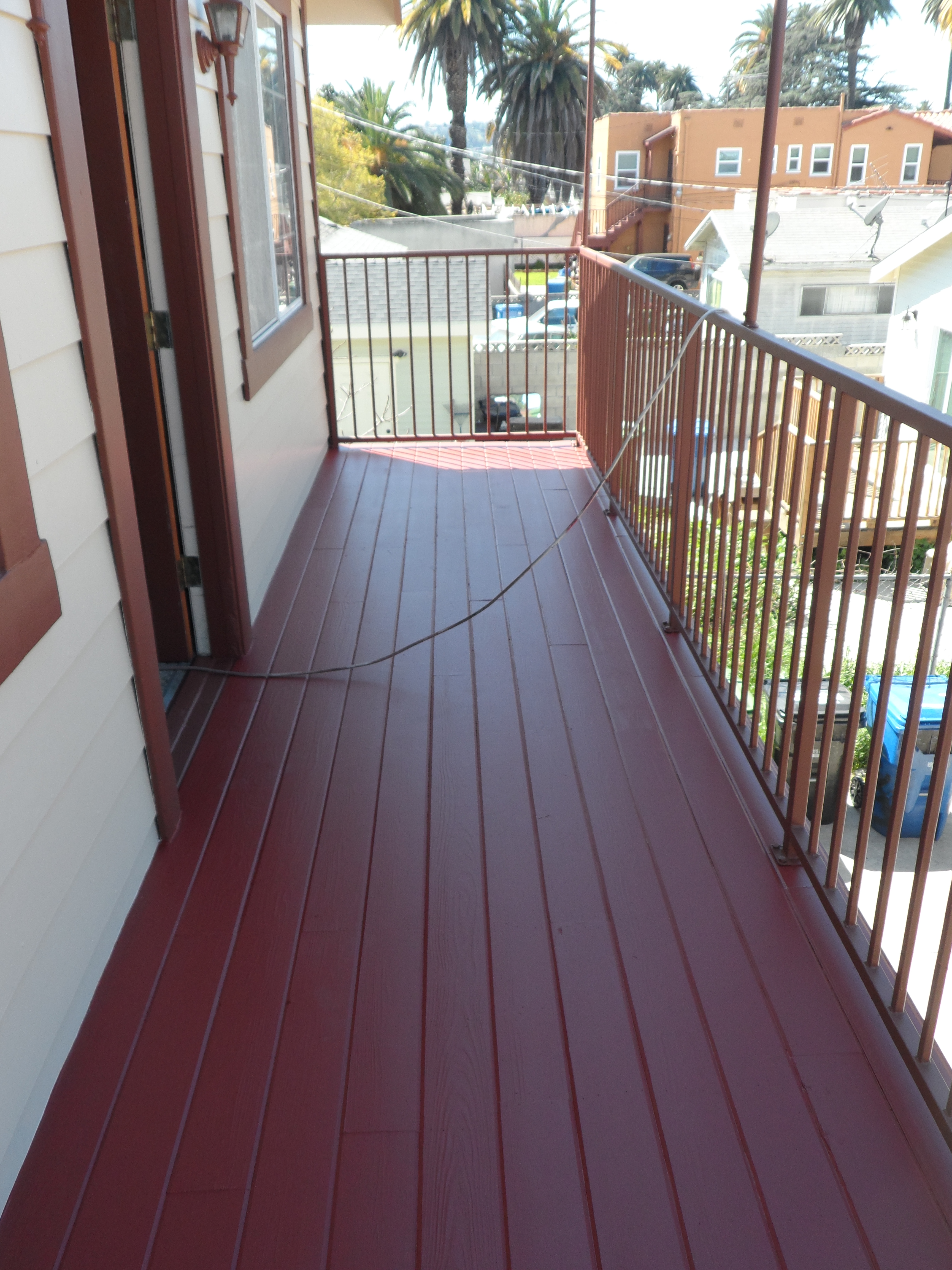 A porch with red paint and a metal railing.