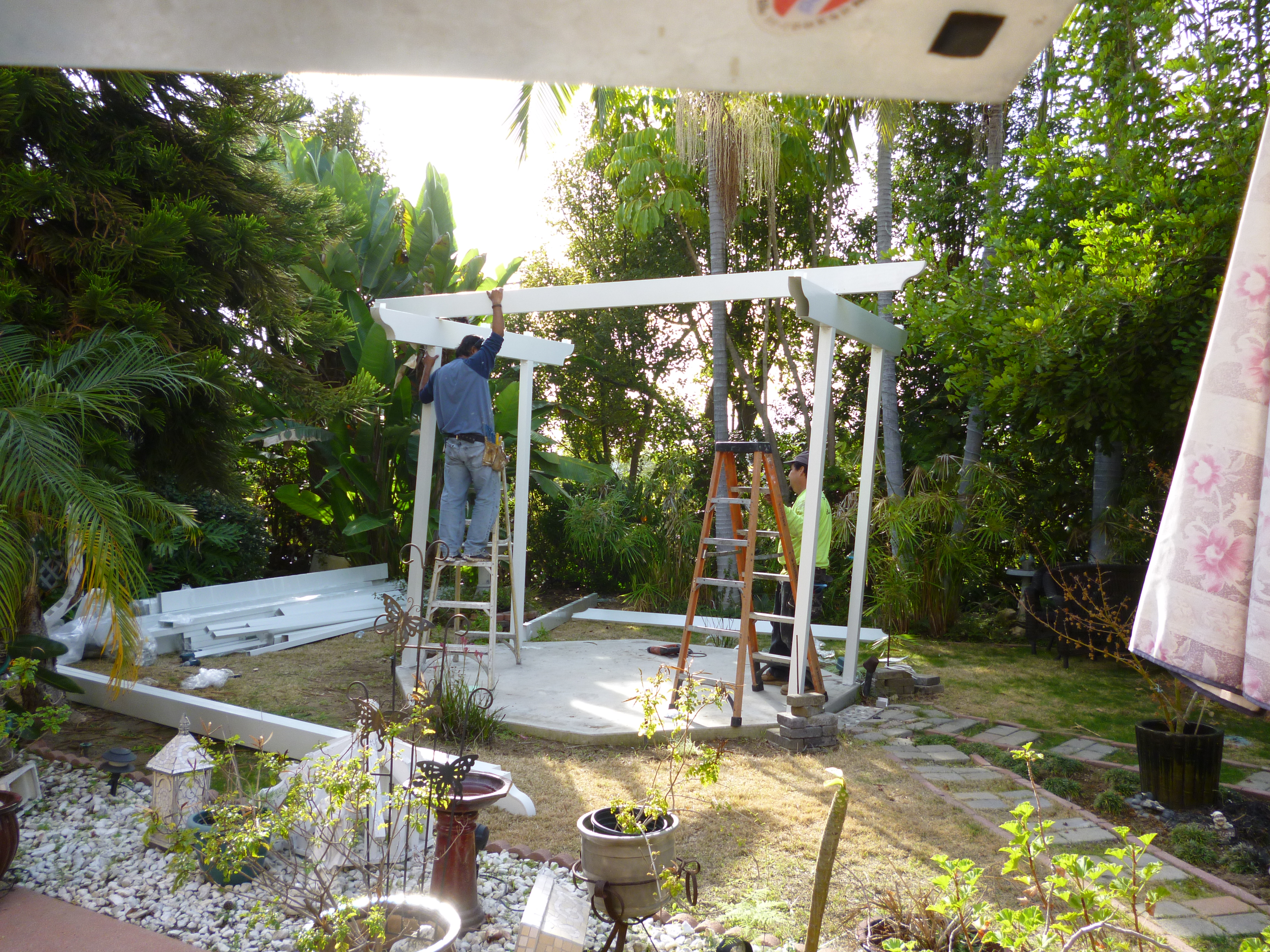 Two men working on a gazebo in the sun.