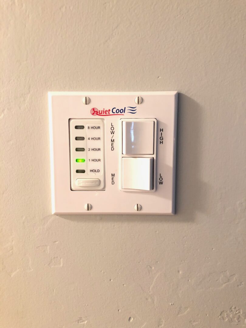 A white wall mounted electrical switch with buttons.