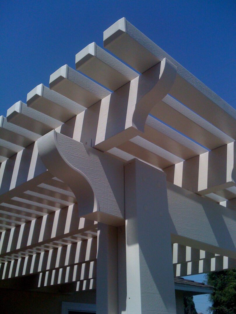 A white pergola with many columns and a blue sky