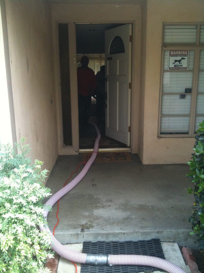 A person is standing in front of a door with a hose.