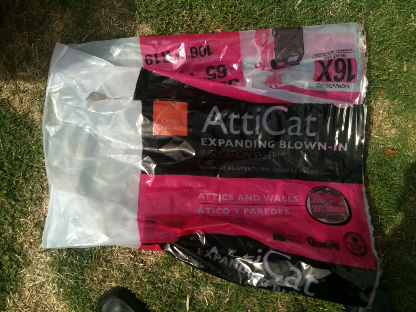 A bag of black and pink tissue paper on the grass.