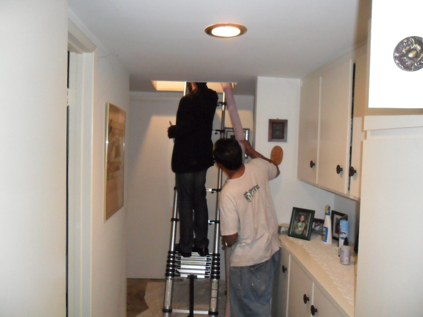 Two people are working on a ladder in the kitchen.