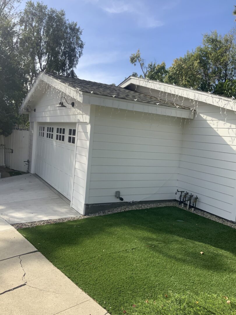 A white garage with grass in the front yard.