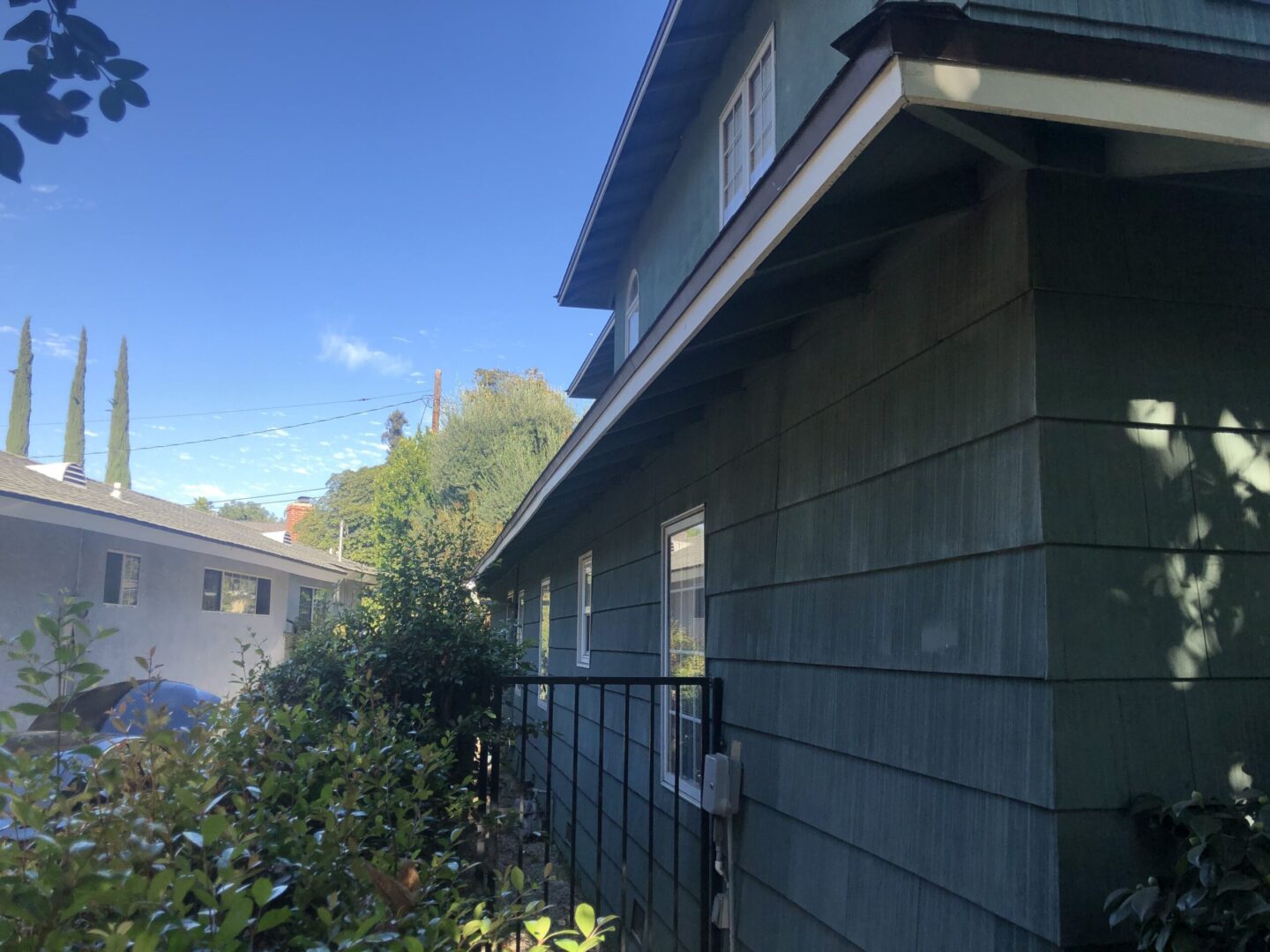 A house with a fence and bushes in the background.