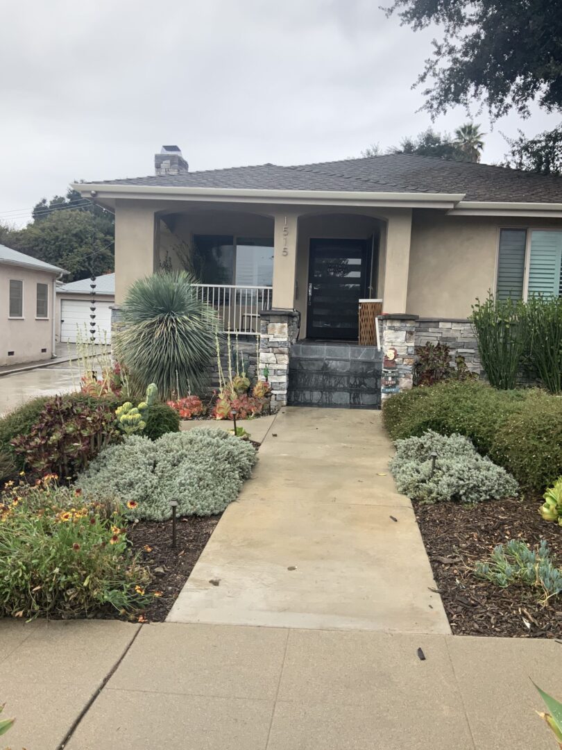 A house with plants and flowers in front of it.