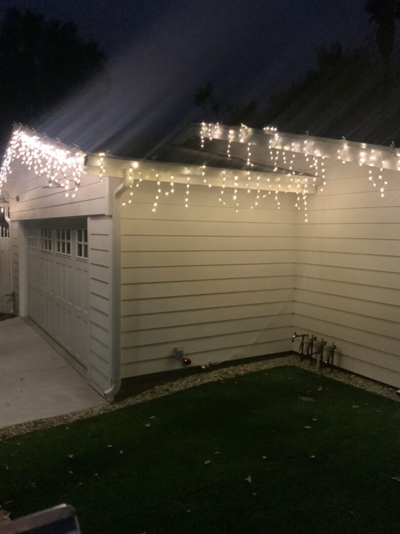 A white shed with lights hanging from it's roof.