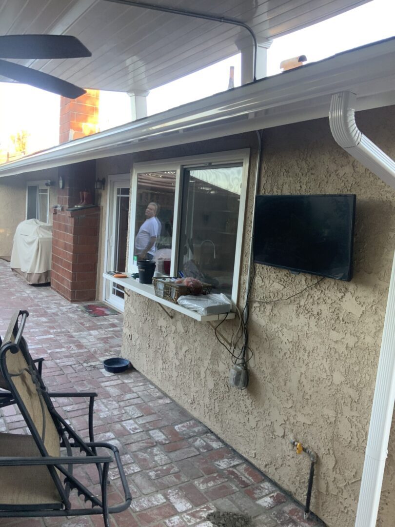 A man standing outside of a house with an open window.