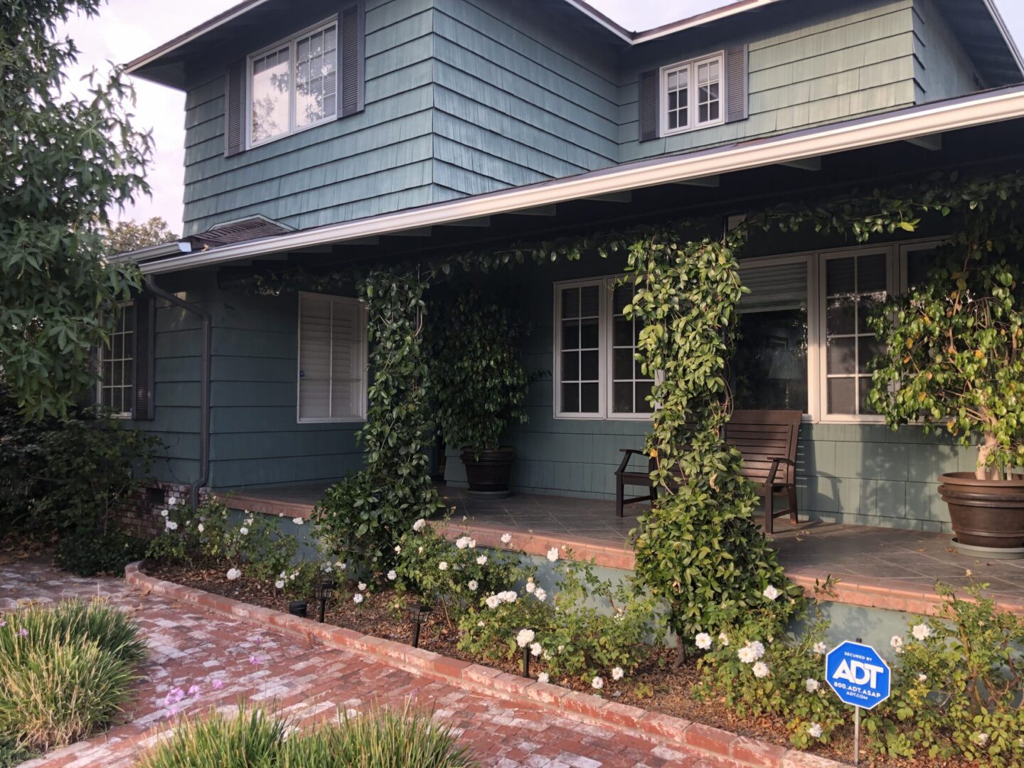 A house with a brick walkway and flowers in the front yard.