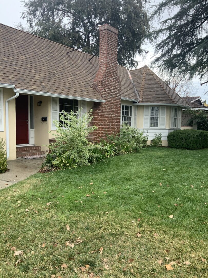 A house with grass and bushes in front of it.