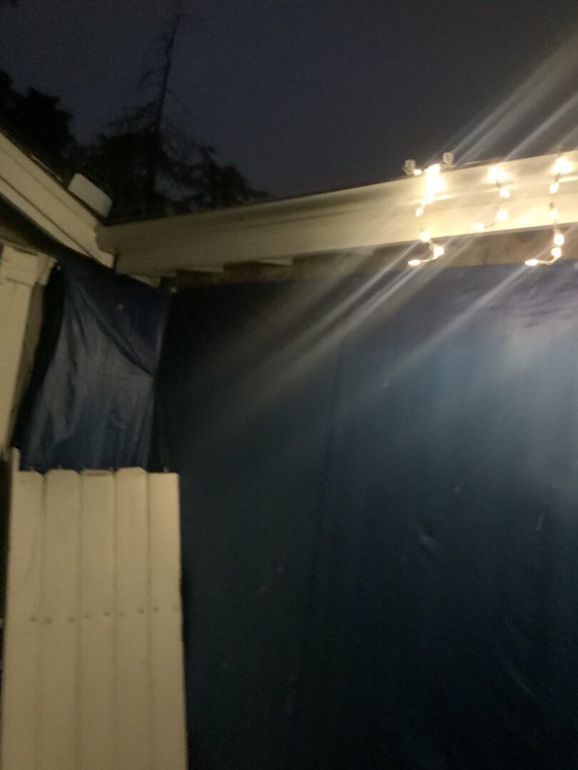 A porch with lights and curtains on the side.