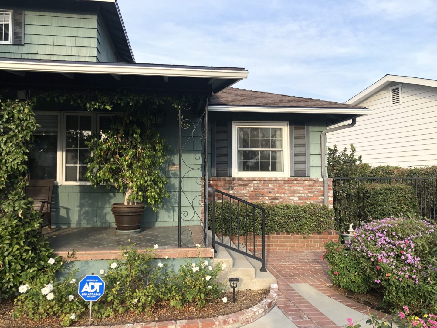 A house with a flower garden and a blue sign.