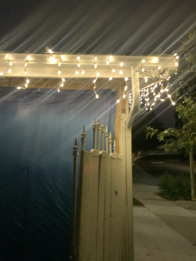 A patio with lights and a fence in the background.